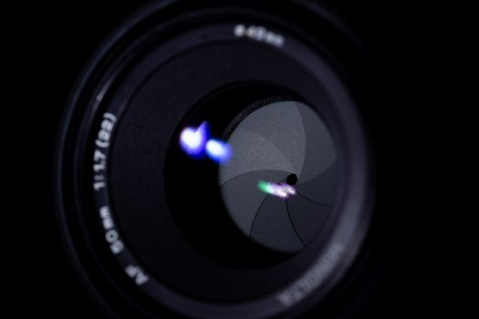 Lens aperture low light photo. Aperture blades is clean. Stock photo with blurred foreground. Isolated on black background.