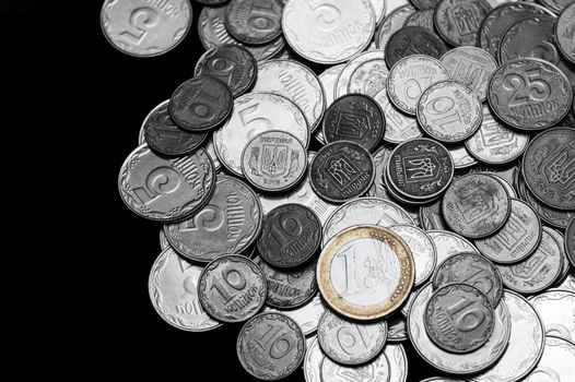 Ukrainian coins with one euro coin isolated on black background. Black and white image.  Euro coin is colored. Close-up view. Coins are located at the right side of frame. A conceptual image.