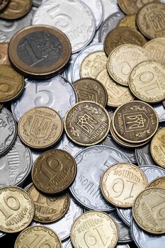 Ukrainian coins with one euro coin isolated on black background. Close-up view. Coins are located at center of frame. A conceptual image.