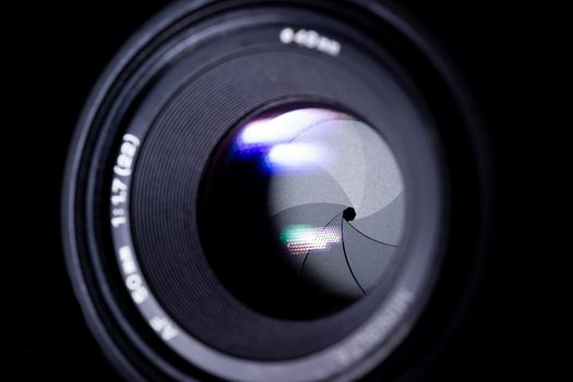 Lens aperture low light photo. Aperture blades is clean. Stock photo with blurred foreground. Isolated on black background.
