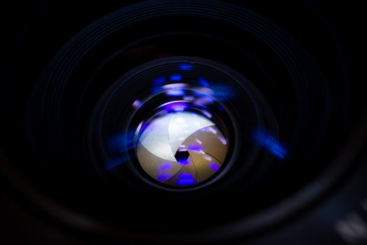 Lens aperture low light photo closeup. Blue traces on glass. Aperture blades is clean. Stock photo isolated on black background.