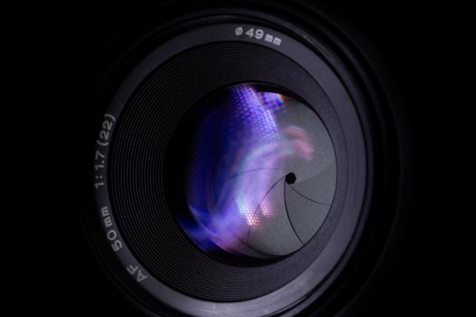 Lens aperture low light photo closeup. Colorful light traces on glass. Aperture blades is clean and dark. Stock photo isolated on black background.