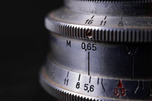 Vintage lens scales symbols closeup. Stock photo with blurred gray background. Aperture symbols and focusing distance sign on lens.