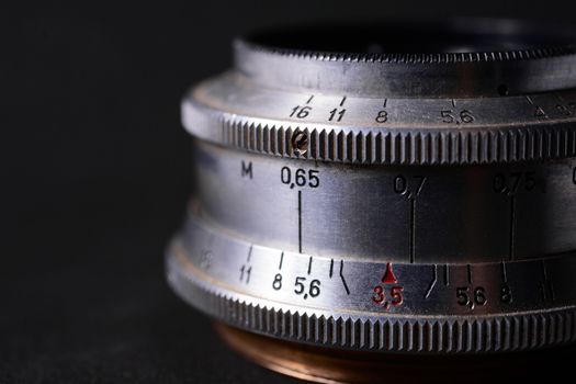 Vintage lens scales symbols closeup. Stock photo with blurred gray background. Aperture symbols and focusing distance sign on lens.