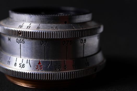 Vintage lens scales symbols closeup. Stock photo with blurred gray background. Aperture symbols and focusing distance sign on lens.