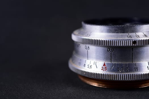 Old vintage lens scales symbols closeup. Photo with blurred gray background. Aperture symbols and focusing distance signs on lens.