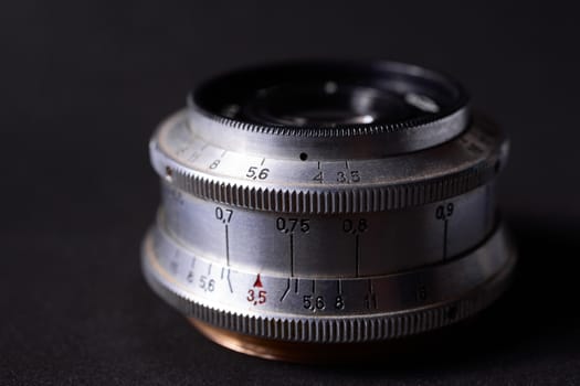 Old vintage lens scales symbols closeup. Photo with blurred gray background. Aperture symbols and focusing distance signs on lens.