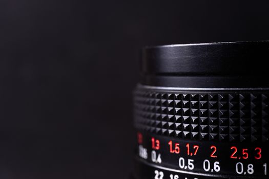Vintage lens scales symbols closeup. Stock photo with blurred gray background. Aperture symbols and focusing distance signs on lens.