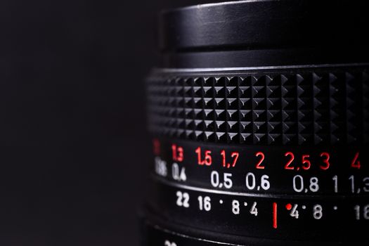 Vintage lens scales symbols closeup. Stock photo with blurred gray background. Aperture symbols and focusing distance signs on lens.
