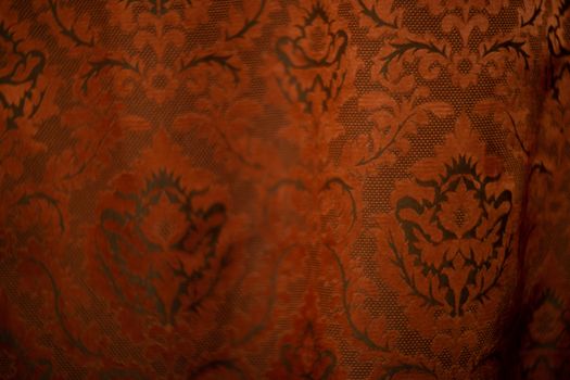 Expensive dark orange home curtains with a very beautiful frilly pattern. Texture shot. Good background or wallpapers.