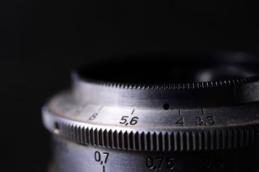 Vintage lens scales symbols closeup. Stock photo with blurred gray background. Aperture symbols and focusing distance sign on lens.