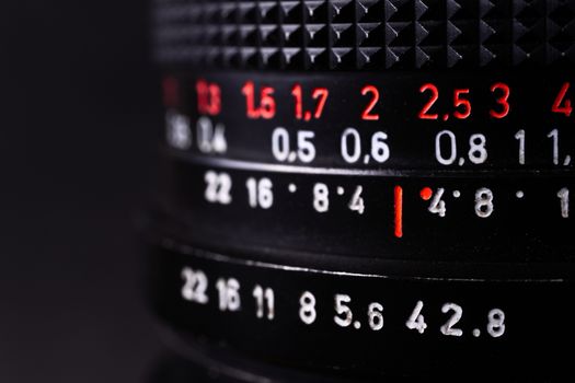 Vintage lens scales symbols closeup. Stock photo with blurred gray background. Aperture symbols and focusing distance signs on lens.