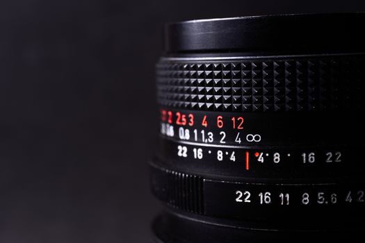 Vintage lens scales symbols closeup. Stock photo with blurred gray background. Aperture symbols and focusing distance signs on lens.