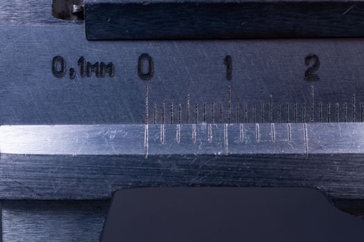 Vintage steel caliper tool closeup. Scale in focus. Tool in very good condition. Scale in metric units, milimeter step. Stock photo on blurred gray background.