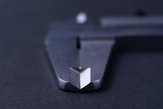 Vintage steel caliper tool closeup. Caliper tips in focus. Tool in very good condition. Scale in metric units, milimeter step. Stock photo on blurred gray background.