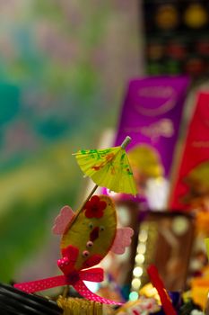 Yellow cocktail paper umbrella on colorful blurred defocused background.