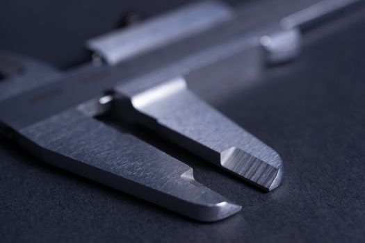 Vintage steel caliper tool closeup. Caliper tips in focus. Tool in very good condition. Scale in metric units, milimeter step. Stock photo on blurred gray background.