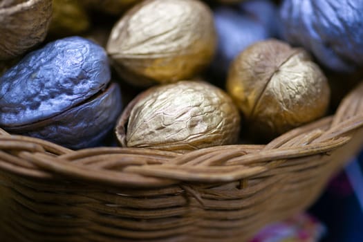 Silver and golden holiday candy nuts in a wicker basket.