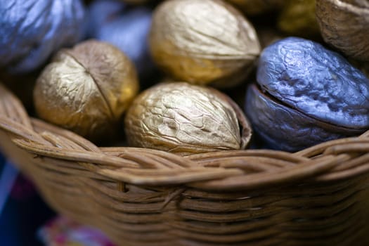 Silver and golden holiday candy nuts in a wicker basket.