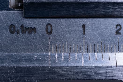 Vintage steel caliper tool closeup. Scale in focus. Tool in very good condition. Scale in metric units, milimeter step. Stock photo on blurred gray background.