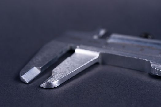 Vintage steel caliper tool closeup. Caliper tips in focus. Tool in very good condition. Scale in metric units, milimeter step. Stock photo on blurred gray background.