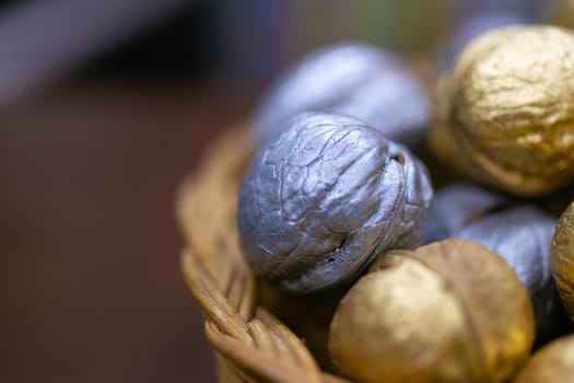 Silver and golden holiday candy nuts in a wicker basket.