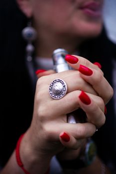 Caucasian woman with red nails manicure and antique ring on finger holds small vape. Smoking alternative vay. Life without cigarettes. Woman-vaper. Small e-cigarette.