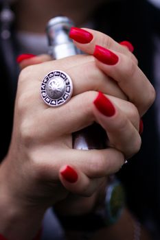 Caucasian woman with red nails manicure and antique ring on finger holds small vape. Smoking alternative vay. Life without cigarettes. Woman-vaper. Small e-cigarette.