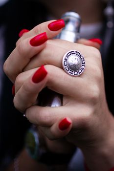 Caucasian woman with red nails manicure and antique ring on finger holds small vape. Smoking alternative vay. Life without cigarettes. Woman-vaper. Small e-cigarette.