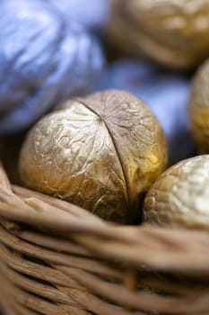 Silver and golden holiday candy nuts in a wicker basket.