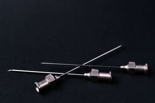 Old rare metallic medical needles isolated on gray background. Needles new and clean. Top view. Sharp needle tips and full metal body.