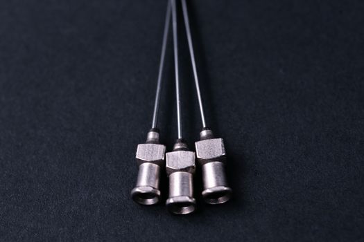 Old rare metallic medical needles isolated on gray background. Needles new and clean. Top view. Sharp needle tips not visible on photo.