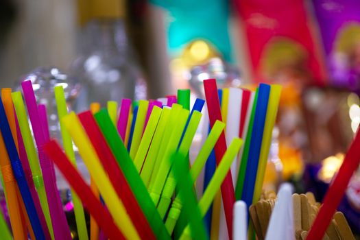 Different colour cocktail plastic pipes on colorful blurred defocused background.