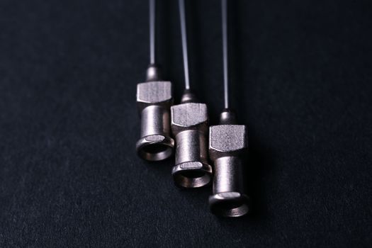 Old rare metallic medical needles isolated on gray background. Needles new and clean. Top view. Sharp needle tips not visible on photo.