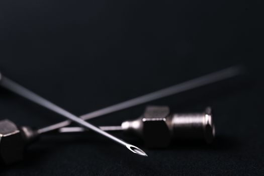 Old rare metallic medical needles isolated on gray background. Needles new and clean. Top view. Sharp needle tips and defocused background.