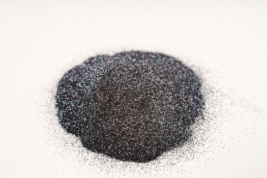 A small bunch of silver blue nail gritter for manicure. Gray tone glitter shining on daylight. Stock photo isolated on white background. Varnish topping on paper.
