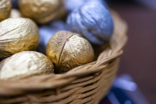 Silver and golden holiday candy nuts in a wicker basket.