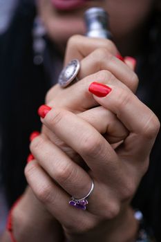 Caucasian woman with red nails manicure and antique ring on finger holds small vape. Smoking alternative vay. Life without cigarettes. Woman-vaper. Small e-cigarette.