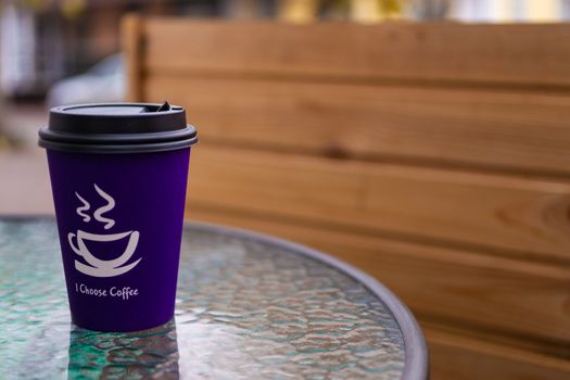 Purple coffee paper cup on glass clear table. On cup wrote: "I choose coffee". Beginning a good day!