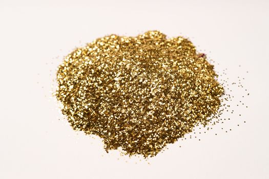 A bunch of golden nail gritter for manicure. Golden glitter shining on daylight. Stock photo isolated on white background. Varnish topping.