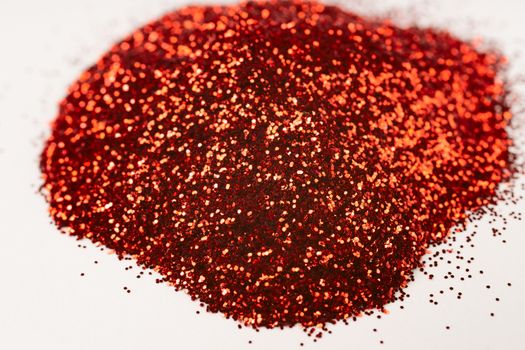 A bunch of hue red nail gritter for manicure. Red glitter shining on daylight. Stock photo isolated on white background. Varnish topping.