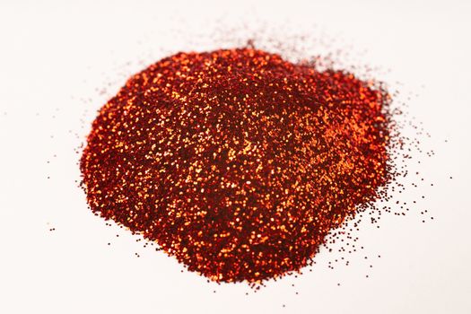 A bunch of hue red nail gritter for manicure. Red and yellow glitter shining on daylight. Stock photo isolated on white background. Varnish topping.