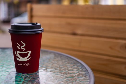 Red coffee paper cup on glass clear table. On cup wrote: "I choose coffee". Beginning a good day!