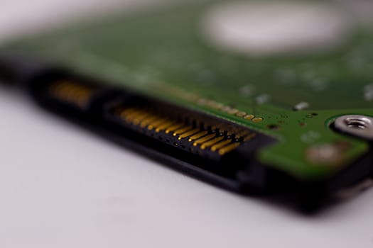 2.5mm laptop HDD on white blurred background. A lot of space on photo is defocused or have soft focus.