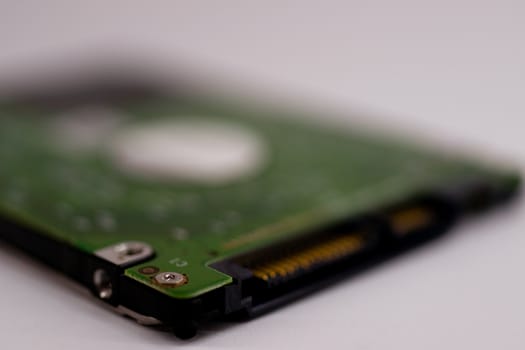 2.5mm laptop HDD on white blurred background. A lot of space on photo is defocused or have soft focus.