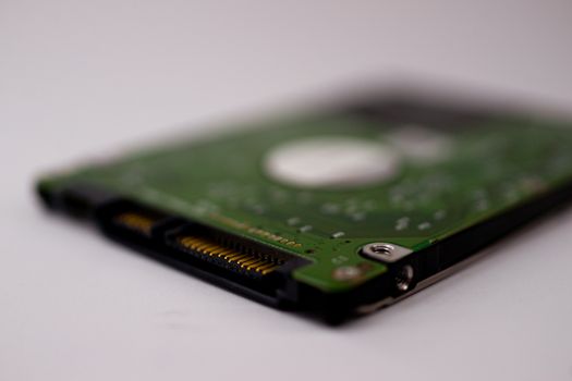 2.5mm laptop HDD on white blurred background. A lot of space on photo is defocused or have soft focus.