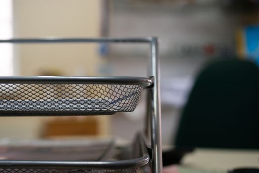 Office metal paper holder on table. Blurred background, partially defocused photo.
