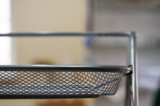 Office metal paper holder on table. Blurred background, partially defocused photo.