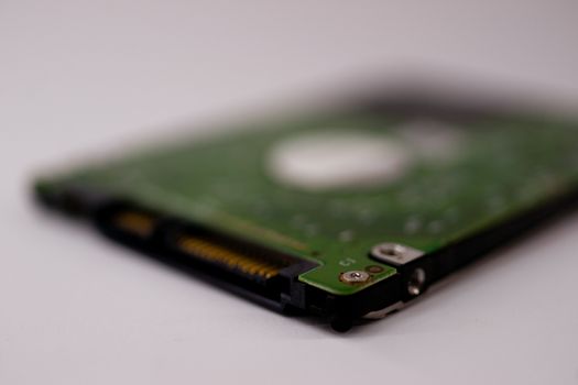 2.5mm laptop HDD on white blurred background. A lot of space on photo is defocused or have soft focus.