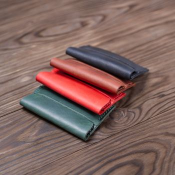 Flat lay photo of four different colour handmade leather one pocket cardholders.  Red, black, ginger and green colors. Stock photo on wooden background.